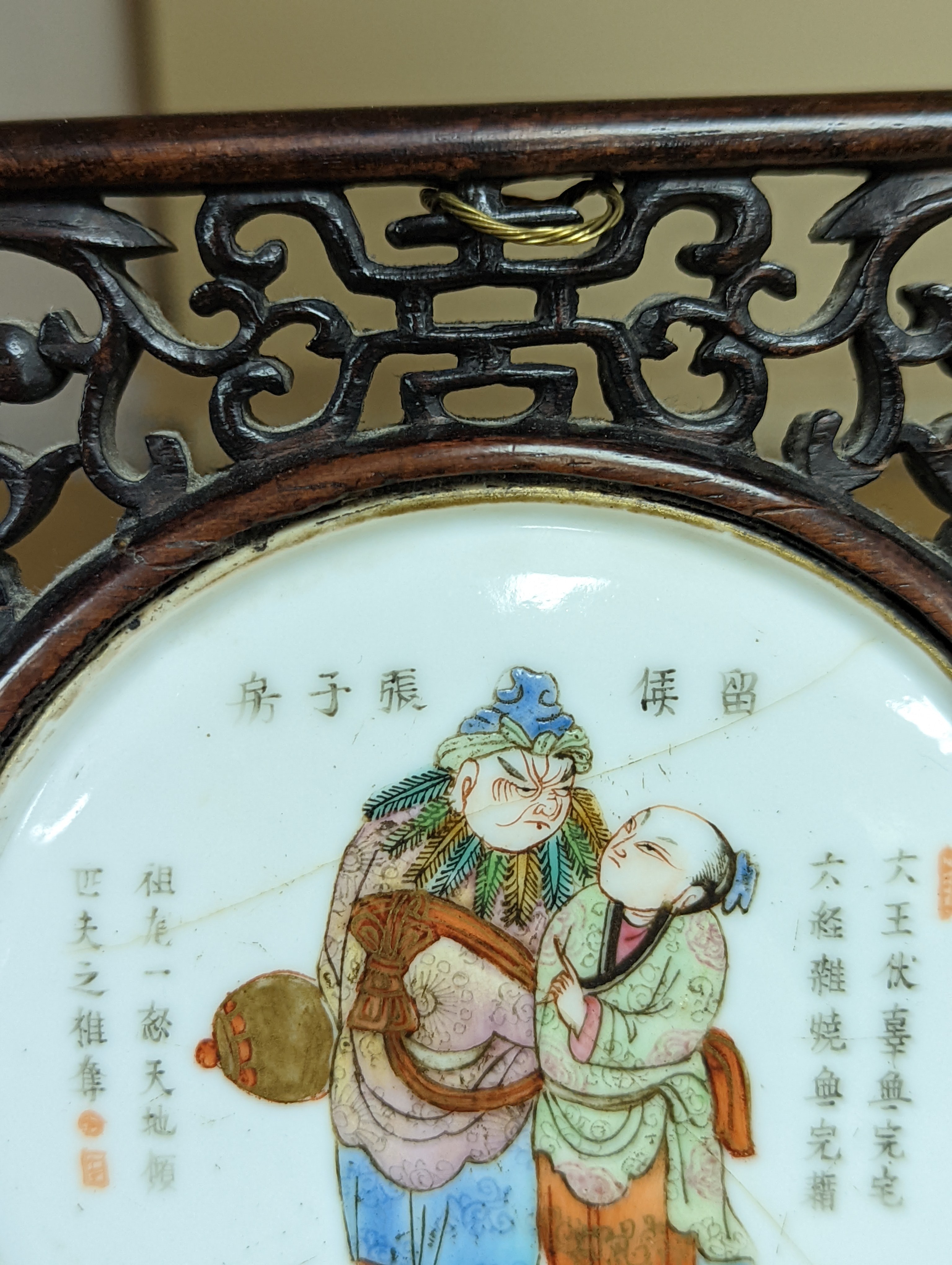 A 19th century Chinese famille rose circular plaque or cover, inset into a wood surround, cracks 15cm sq